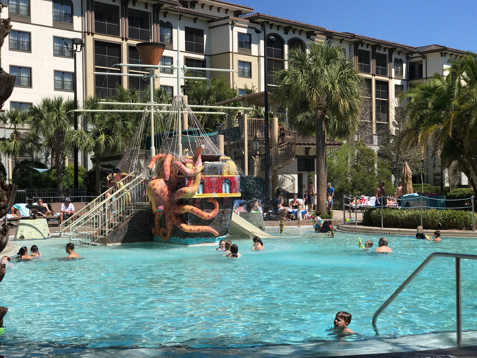 Children playing in a splash pool with slides and a pirate-ship play area