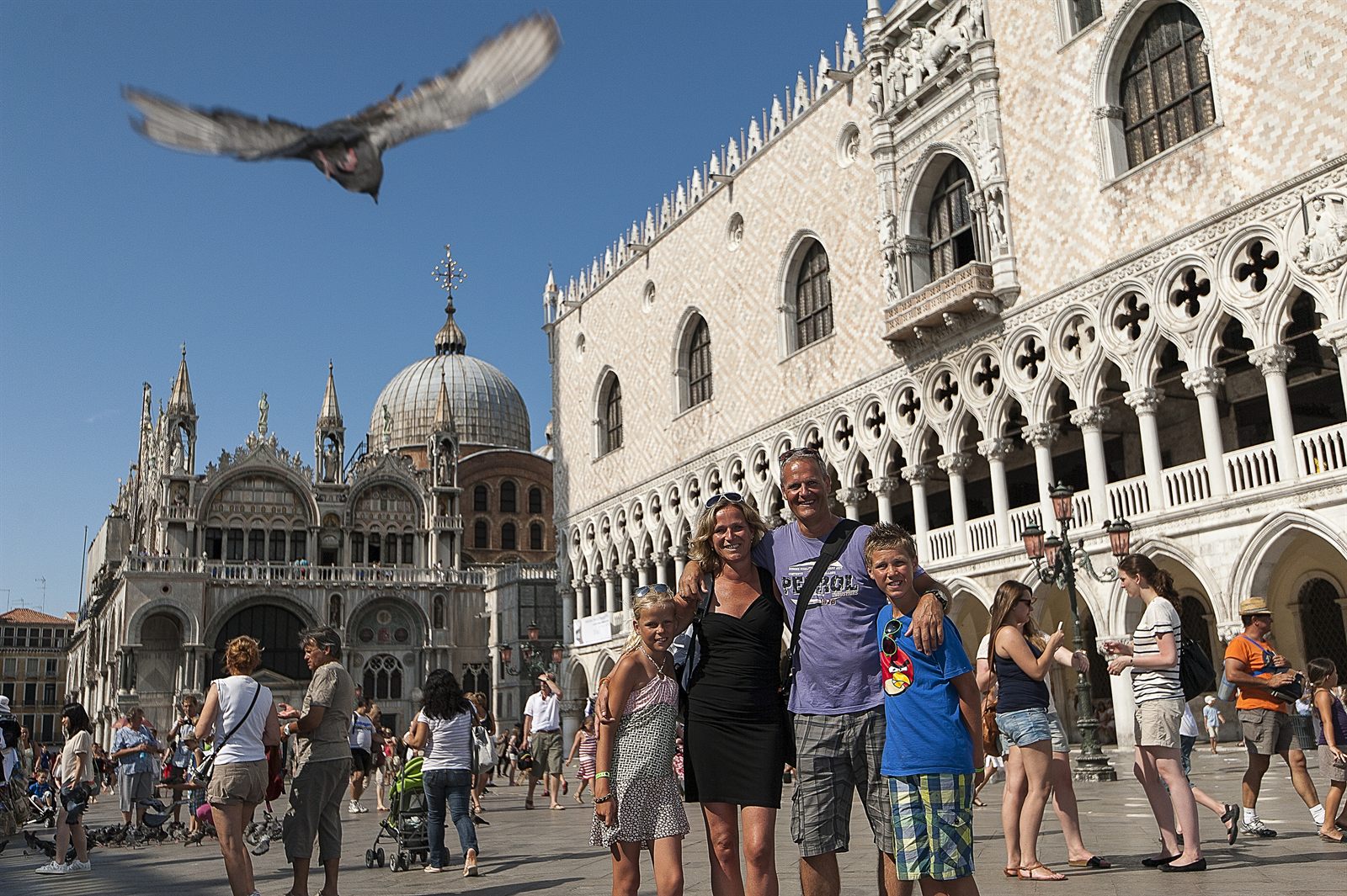 Family smiling together in a busy St. Mark’s Square in Venice